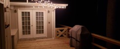 Kitchen-Aid gas grill at night with deck lighting overhead
