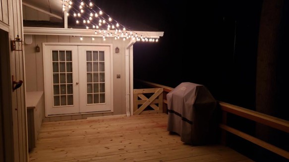 Kitchen-Aid gas grill at night with deck lighting overhead